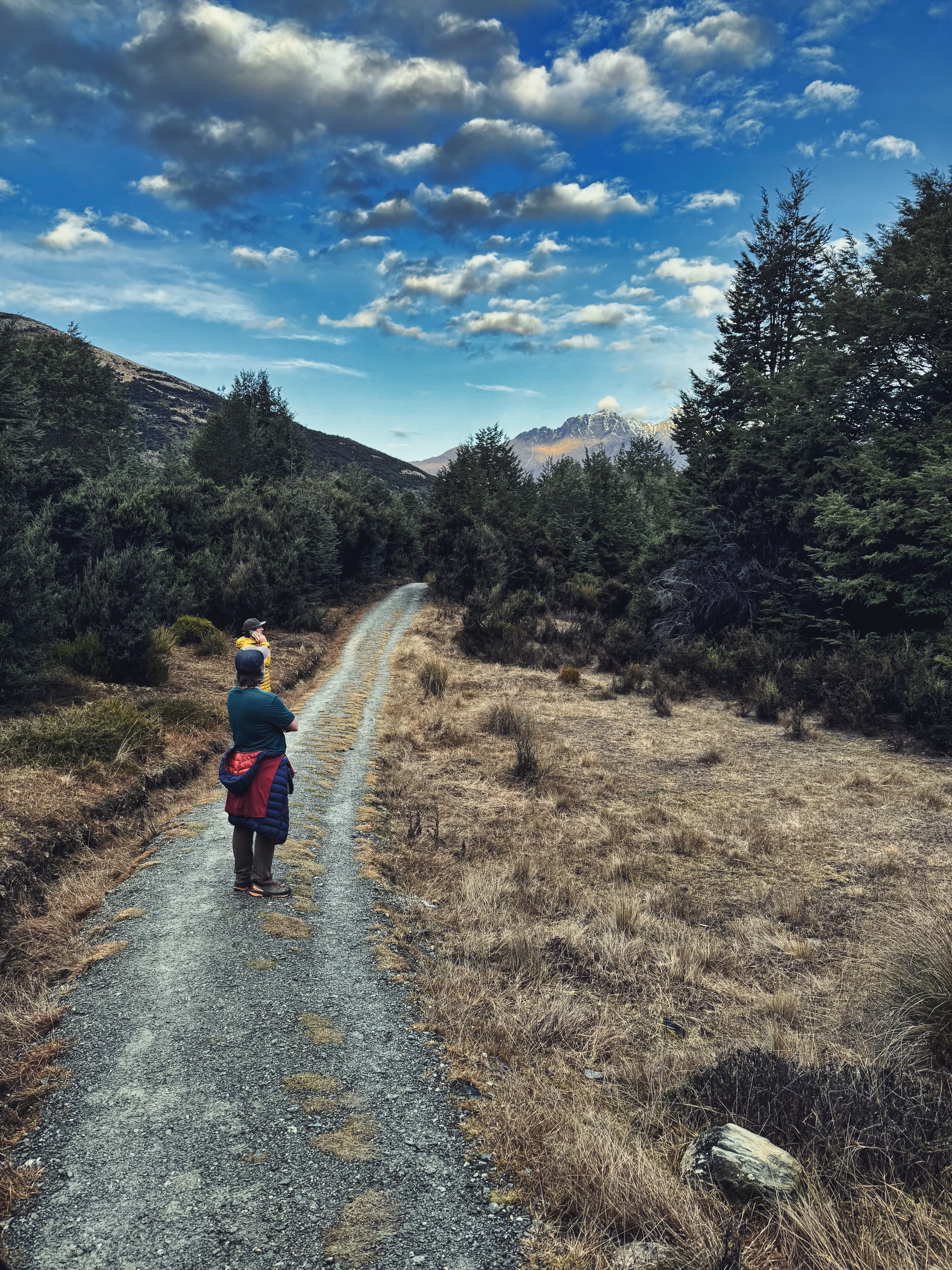 Two figures on a remote track outside Queenstown, the Southern Alps ahead